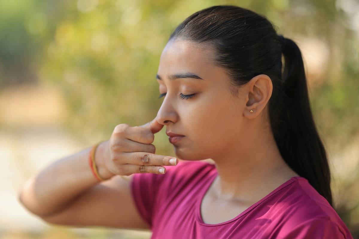 Woman practicing Deep Breathing while gently squeezing a breath ball on a yoga mat